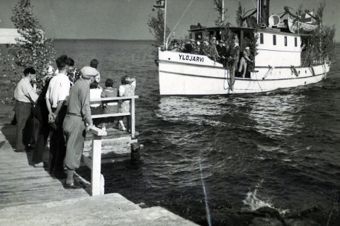 Henkilöt seisovat laiturilla. Satamaa lähestyy Ylöjärvi-laiva.