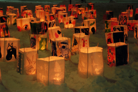 Paperilyhtyjä lumihangessa. Lyhdyt on koristeltu piirroskuvilla.