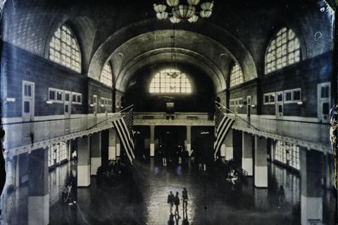 Mustavalkoisessa kuvassa on iso asemahalli. Hallissa kävelee muutamia ihmisiä ja Yhdysvaltojen liput liehuvat parvelta.