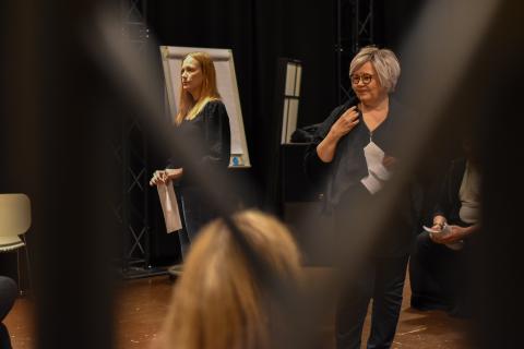 Kaksi henkilö seisoo harjoituslavalla.