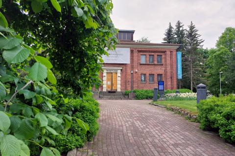 Tampereen taidemuseon tiilirakennus näkyy osittain vihreän kasvuston takaa.