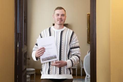 Mies pitelee käsissään paperia. 