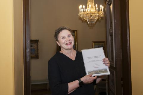 Nainen pitelee edessään papereita.