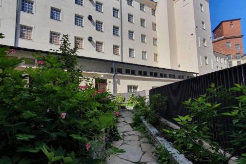 Maan tasalta kuvattu tehdaspuutarha Finlaysonin valkoisen rakennuksen edustalla.