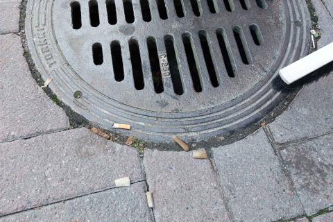 Tupakantumppeja katukaivon luona.