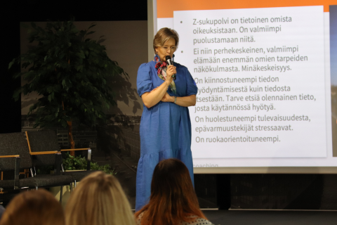 Marjaana Herveli seisoo lavalla diaesityksensä edessä.