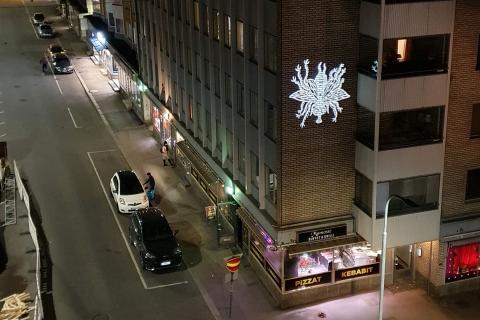 Kuva kadulta pimeän aikaan. Rakennuksen seinään on heijastettu hyönteisen kuva. 
