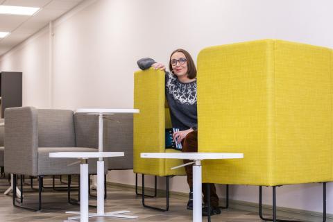 Nainen kurkistaa värikkään työnurkkauksen sisältä.