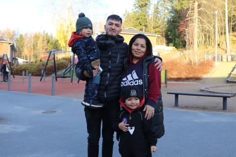 Perhe, kaksi aikuista ja kaksi lasta päiväkodin pihalla.