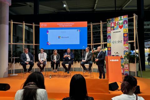 Panelistit keskustelemassa lavalla, taustalla lukee Microsoft.