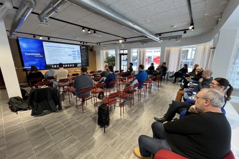 Henkilöitä istumassa kokoustilassa.