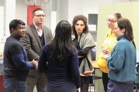 Small group of people standing in circle and talking to each other.