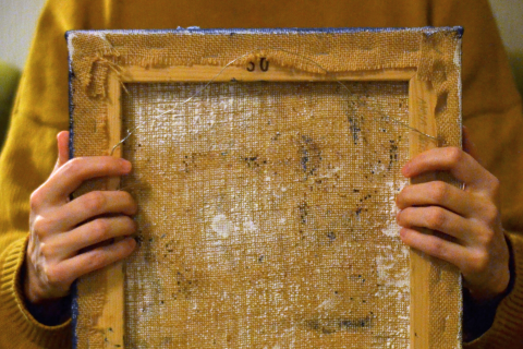 Ihminen pitää sylissään nurinpäin olevaa maalausta.