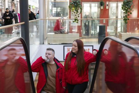 Tullintorin naapurustotyön punatakkiset työntekijät nousevat ylöspäin liukuportaissa.