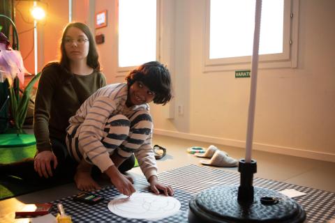 Hymyilevä lapsi istuu naisen sylissä ja piirtää.