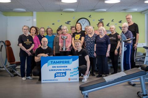 Seniori-ikäisiä ryhmäkuvassa kuntosalilla Uno-pokaalin kanssa.