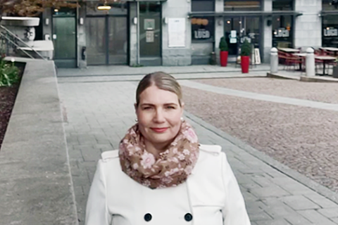 Saila Hämäläinen seisoo Frenckellinaukion reunalla kukkivien kirsikkapuiden alla.