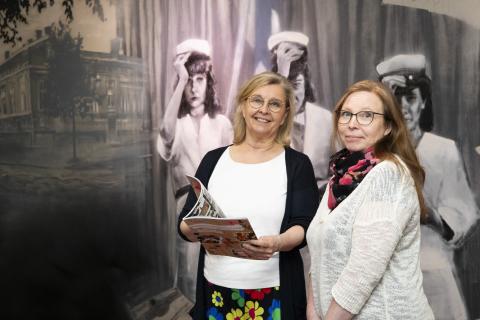 Tuija Flink and Outi Suominen look at the camera in the corridor of Tampere Upper Secondary School of Performing Arts.