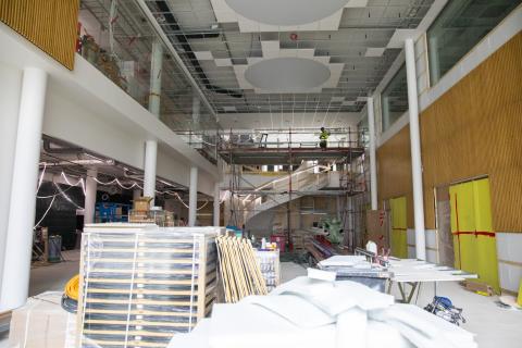 Korkea aula, jonka etuosassa on rakennustarvikkeita kasoittain ja takana kulkevat kaarevat portaat.