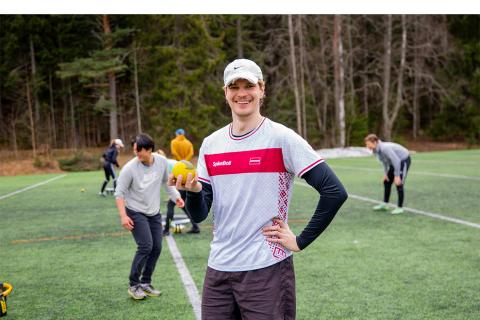 Simeon Seitz smiles for the camera with a ball in hand on the grass pitch in Koivistonkylä.