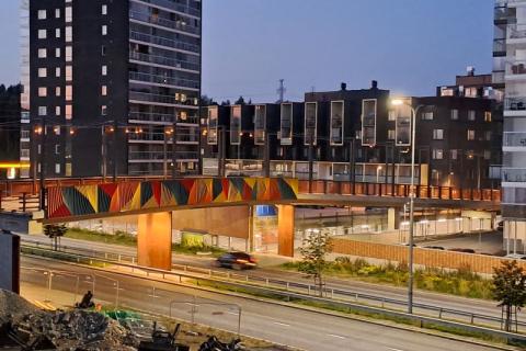 Kävely- ja pyöräilysilta värikkäine kaiteineen yöaikaan Hervannassa.