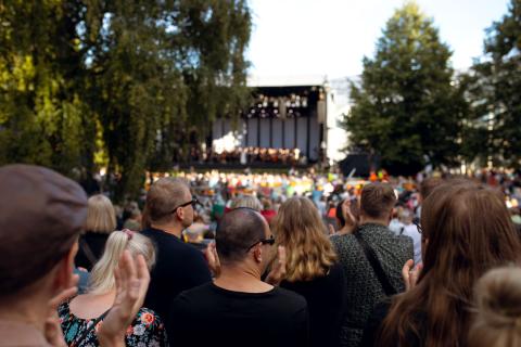 A large crowd listening to the Tampere Philharmonic&#039;s park concert in the lush Sorsapuisto Park.