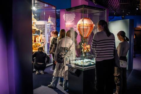 Näkymä Muumimuseon näyttelystä, jossa teoksia vitriineissä ja ihmisiä katselemassa niitä.