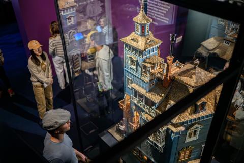 Näkymä Muumimuseon näyttelystä, jossa teoksia vitriineissä ja ihmisiä katselemassa niitä.