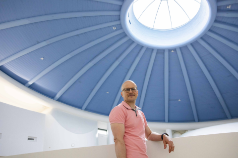 Henkilö seisoo sinisen kattokupolin alla ja nojaa kaiteeseen.