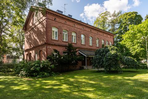 Hatanpään kartanon konttorirakennuksen punatiilinen julkisivu ja piha-aluetta.