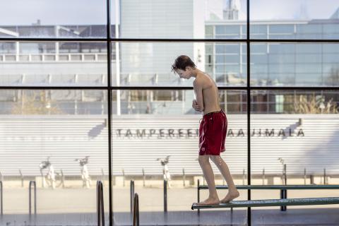 Poika hyppäämässä uima-altaaseen 