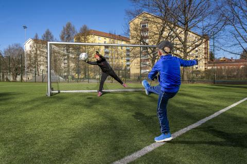 Poika potkimassa palloa maaliin 