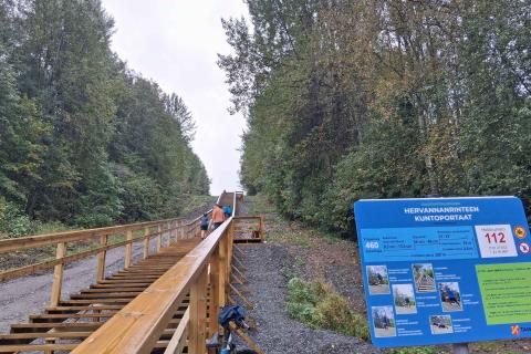 Kuntoilijoita kuntoportailla ja opastaulu rinteen juurella.