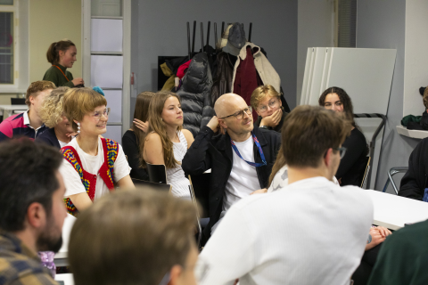 Monta eri-ikäistä henkilöä kuuntelee tarkkaavaisena puhetta.