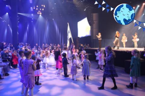 Children dancing in front of the stage. Dance instructors on stage teaching dancing. 