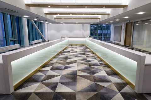 Sali, jota hallitsee suuri vaalea pöytä ja kokolattiamatto, jossa on kolmioita.