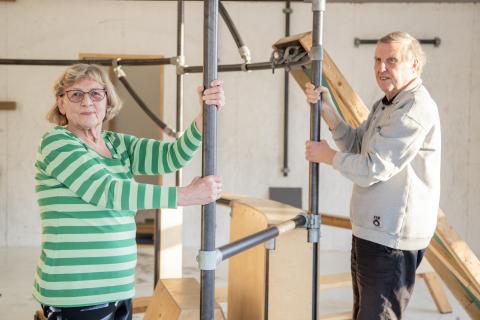 Nainen ja mies pitävät kiinni metallitangoista liikuntasalissa.