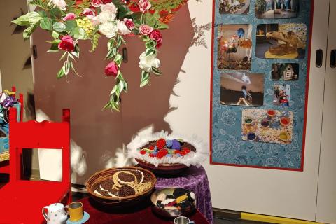 Värikäs kukkasilla korsiteltu sateenvarjo lasten juhlapöydän yläpuolella. 