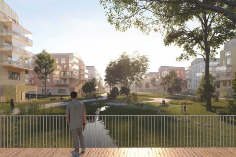 Kuvassa henkilö katselee sillalta vehreää vesiuomaa, taloja taustalla. 