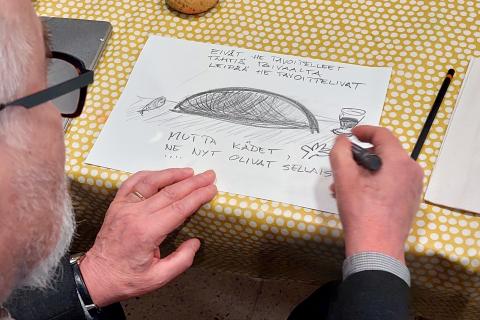 Harmaapartainen mies piirtää grafiittiliidulla taidekuvaa paperille.