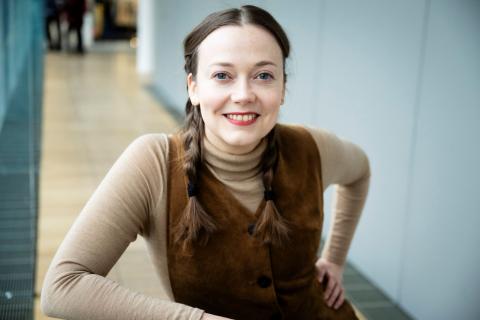 Aino-Maria Kangas seisoo. Taustalla näkyy tyhjä käytävä. 