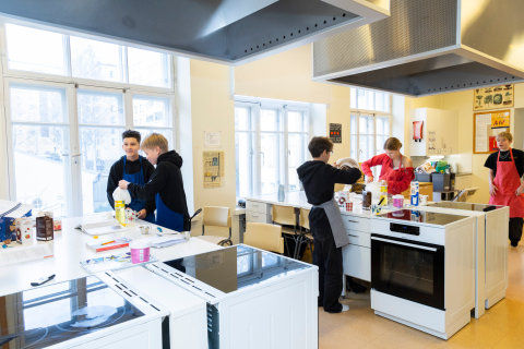 Useita oppilaita leipoo kotitalousluokassa.