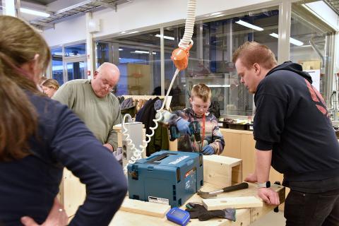 Neljä henkilöä tekee töitä tai katsoo linnunpönttöjen äärellä.