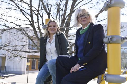 Kaksi iloista naista istumassa aidan reunalla