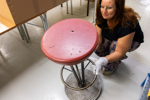 Työväenmuseossa Werstaassa työskentelevä asiantuntija on kyykyssä tarkastelemassa baarijakkaraa.