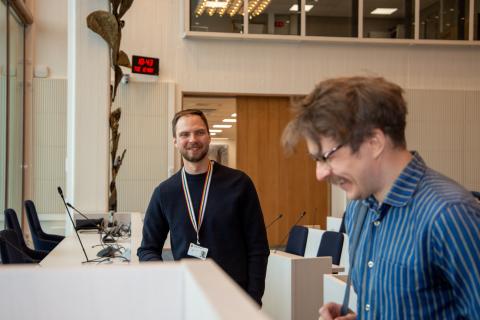 Mikael seisoo kuvassa taustalla ja katsoo Henrikiä, joka on kuvassa sivuittain ja hymyilee leveästi silmät lähes suljettuina.