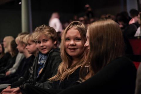 Kahdeksasluokkalaiset istuvat teatterin katsomossa ja odottavat esityksen alkamista