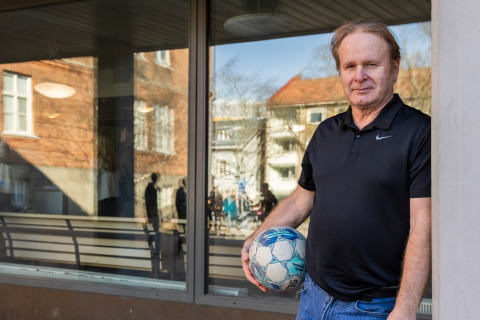 Jussi Melko nojaa pylvääseen jalkapallo kädessään koulun pihalla.