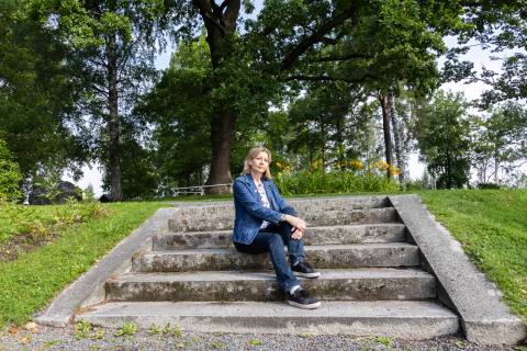 Henkilö istuu vanhoilla portailla keskellä puistoa.