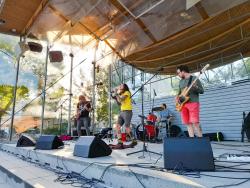 Laulaja ja soittajat lavalla puistokonsertissa.